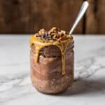 Creamy blended brownie batter overnight oats in a glass jar with toppings.