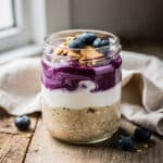 High protein blueberry cheesecake oats in a creamy layered glass jar