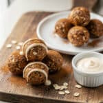 Cinnamon roll protein balls with creamy drizzle on rustic wooden board.