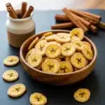 Crispy cinnamon sugar banana chips in a rustic wooden bowl.
