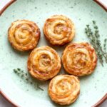 Golden brown fig and goat cheese pinwheels on rustic board