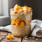 Creamy peach cobbler protein oats in a rustic glass jar breakfast.