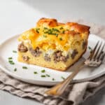 Easy breakfast casserole with sausage eggs and cheese on white plate.