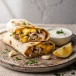 Cheesy garlic chicken wraps with creamy filling on a rustic wooden board.