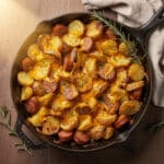 Creamy cheesy ranch potatoes and smoked sausage in a cast iron skillet.