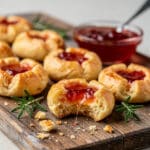 Golden cheesy thumbprint appetizers filled with vibrant hot pepper jelly.