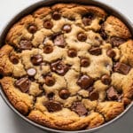 A thick homemade chocolate chip cookie cake slice with melted chocolate chips.