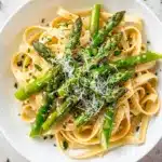 Creamy asparagus pasta with parmesan sauce in a white ceramic bowl.