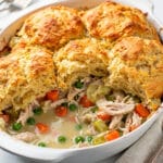 Creamy chicken pot pie casserole with golden flaky biscuit topping in ceramic dish