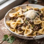 Creamy Parmesan garlic beef bowtie pasta in a rustic white bowl.