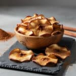 Crispy air fryer cinnamon apple chips in a rustic wooden bowl