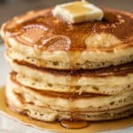 Fluffy buttermilk pancakes with fresh berries and maple syrup on plate