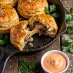 Golden garlic Parmesan cheeseburger bombs with melted cheese interior in skillet.