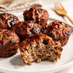 Golden brown meatloaf muffins with a sticky ketchup glaze on a white plate.