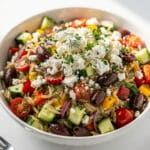 Colorful Greek orzo pasta salad with tomatoes, cucumber, feta, and olives.