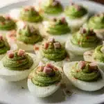 Green eggs and ham deviled eggs with creamy filling on white plate