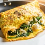 Golden spinach feta omelet with crispy edges and soft cheesy interior.