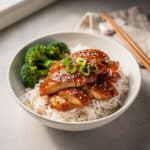 Sticky chicken rice bowl with broccoli and green onion garnish.