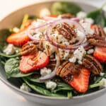 Vibrant strawberry spinach salad with feta cheese and candied pecans in a bowl.