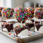 Colorful truffula tree marshmallow pops with sprinkles and glossy chocolate coating.