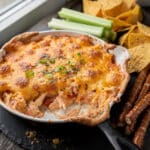 Creamy baked buffalo chicken dip with cheese and celery dippers.