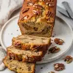 Moist banana nut bread slice with walnuts on rustic wooden board
