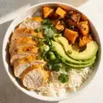 Healthy chicken sweet potato rice bowl with avocado and fresh herbs.