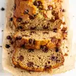 Moist chocolate chip banana bread with melty chips on rustic cutting board