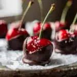 Chocolate dipped cherries with glossy dark coating and flaky sea salt.