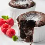 Chocolate lava cakes reveal molten centers with raspberries and powdered sugar.
