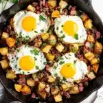 Crispy corned beef hash skillet topped with four sunny side up eggs