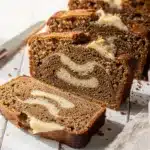 Moist banana bread slice with creamy swirl on rustic wooden cutting board