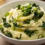 Creamy colcannon mashed potatoes with cabbage and melting butter in a bowl.