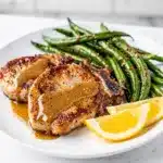 Honey Dijon pork chops and green beans on a rustic ceramic plate.