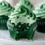 Green velvet cupcakes with mint cream cheese frosting on a rustic wooden table.