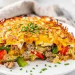 Golden brown hash brown breakfast casserole slice with sausage and peppers.