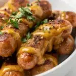 Honey mustard cocktail sausages in a glossy sticky sauce with fresh parsley.