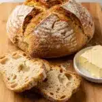 Golden brown Irish soda bread slice with melting butter on rustic board.