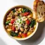 Creamy Italian sausage and white bean soup in a rustic ceramic bowl.
