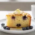 Moist lemon blueberry pound cake slice with fresh berries and powdered sugar.