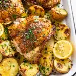 Crispy lemon pepper chicken thighs with roasted potatoes and fresh parsley.