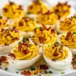 Creamy loaded deviled eggs with crispy bacon and shredded cheddar cheese.