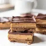No bake chocolate peanut butter bars with creamy topping on white plate