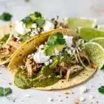 Slow cooker salsa verde chicken tacos with fresh toppings and vibrant colors.