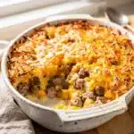 Sausage and hash brown breakfast casserole recipe in a white baking dish.
