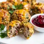 Golden brown sausage stuffing balls with herbs and cheese on rustic board
