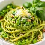 Spring pea pesto pasta with creamy sauce and fresh lemon wedge