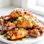 Sticky honey soy chicken drumsticks with sesame and green onion garnish.