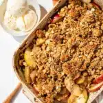 Warm apple crisp with vanilla ice cream in a rustic ceramic dish.