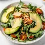 Fresh arugula salad with lemon vinaigrette topped with Parmesan and pine nuts